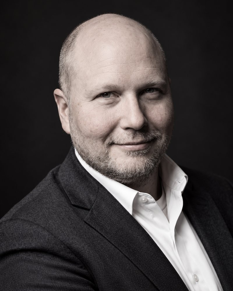 Andrew Spencer in a dark jacket and open-collar white shirt